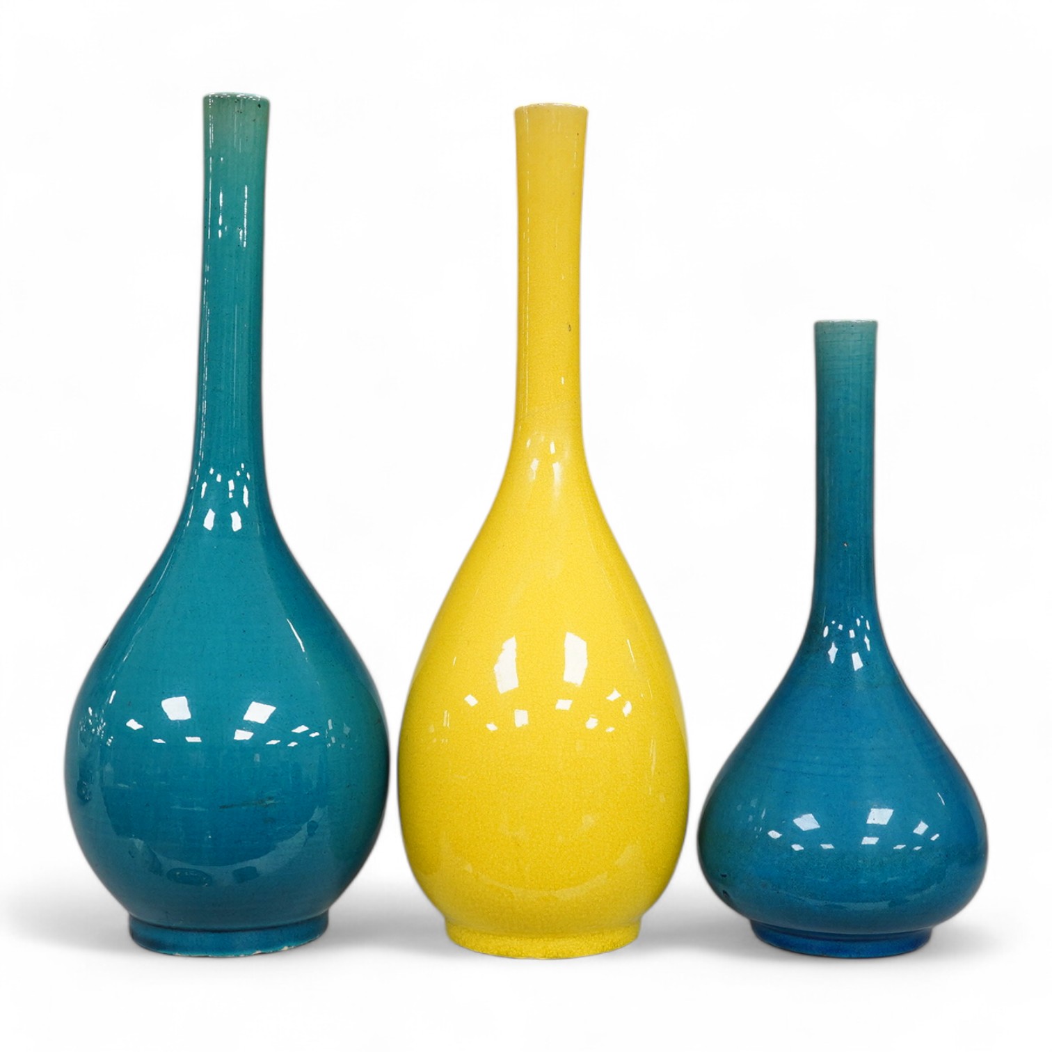 A late 19th century Japanese turquoise glazed narrow neck bottle vase, 31cm high, a smaller similar vase, 22cm high and a tall yellow glazed vase, 31cm high. Condition - repair to neck of yellow vase